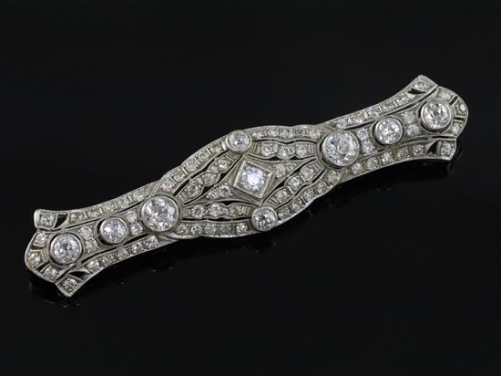 A 1920s pierced platinum? and millegrain set diamond bar brooch, 72mm.